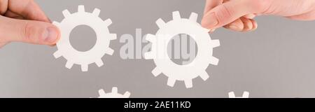 cropped view of people holding white gears isolated on grey, panoramic shot Stock Photo