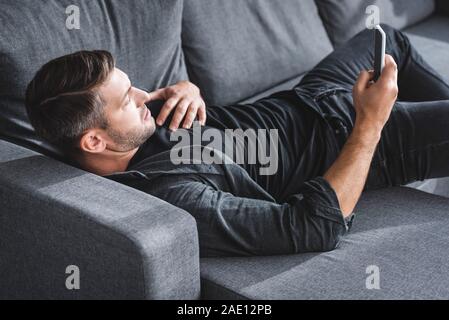 high angle view of handsome man having heart attack and using smartphone in apartment Stock Photo