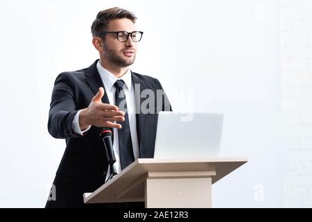 businessman in suit standing at podium tribune and speaking during conference isolated on white Stock Photo