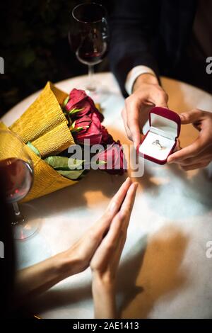cropped view of man presenting wedding ring to girlfriend while making marriage proposal Stock Photo