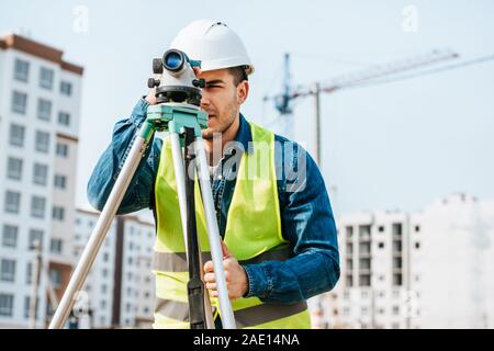 Surveyor looking throughout digital level on construction site Stock Photo