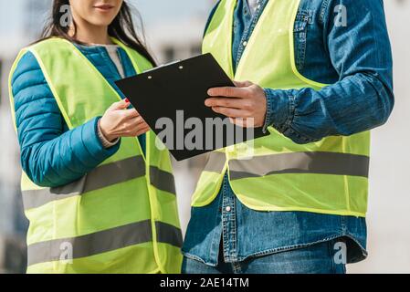 Cropped view of Surveyors in high visibility jackets holding clipboard Stock Photo