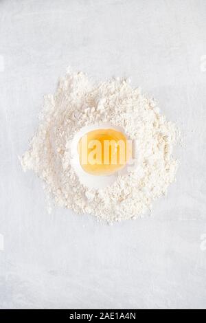 Raw egg in flour on a white tile background. Baking ingredients Stock Photo