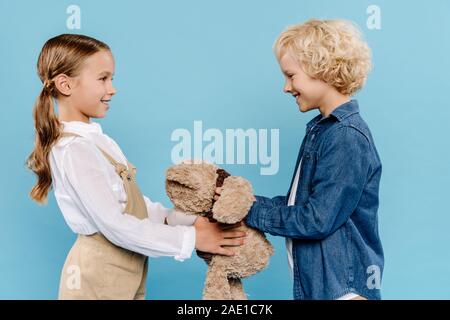 smiling and cute kids holding teddy bear isolated on pink Stock Photo ...
