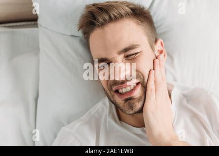 top view of young man touching cheek while suffering from toothache Stock Photo