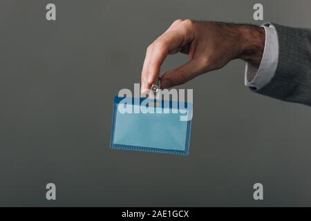 Cropped view of man holding badge isolated on grey Stock Photo