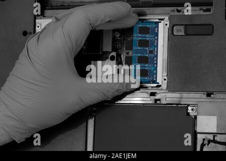 Technician installing RAM into the memory slot on a laptop computer.  Abstract image with selective colour Stock Photo