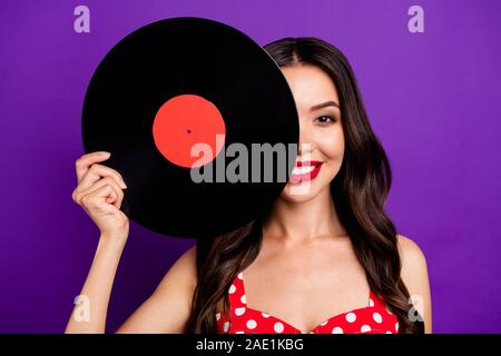 Close-up portrait of her she nice attractive lovely cheerful cheery wavy-haired girl holding in hand hiding face behind vinyl isolated on bright vivid Stock Photo