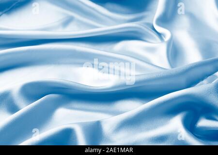 Background in satin pink fabric draped in classic blue waves. Trend monochrome tinting. Copy space of horizontal frame. Place for design text. Stock Photo