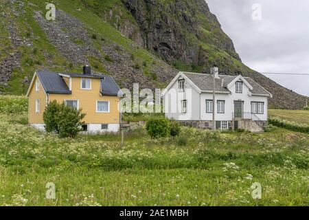 Arctic circle fjord cityscape with traditional houses in green blossoming meadows, shot under bright cloudy light near Eggum,  Lofoten, Norway Stock Photo