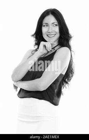 Studio shot of young happy businesswoman smiling while thinking and looking up Stock Photo