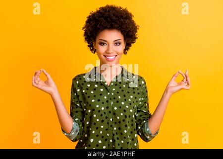 Photo of beautiful dark skin lady holding hands om position meditating morning relaxation body refreshment wear green dotted shirt isolated yellow Stock Photo