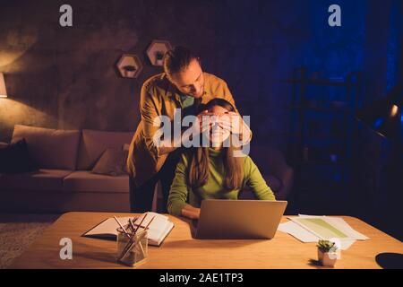 Portrait of his he her she nice attractive lovely cheerful cheery spouses guy covering girl's eyes working self developing help assistance at night Stock Photo