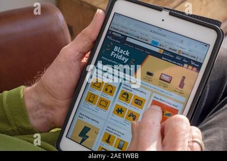 Close up of person man looking ordering shopping ordering at Amazon black Friday internet on line website homepage on Ipad England UK Great Britain Stock Photo