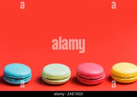 Sweet and colourful french macaroons or macaron on red background with copy space. Dessert, homemade cake Stock Photo