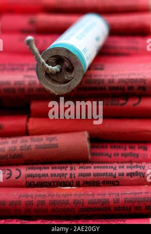 Berlin, Germany - December 5, 2019: Newspaper sealing of a Chinese firecracker on a pile of red firecrackers ('Böller') from the German market. Stock Photo