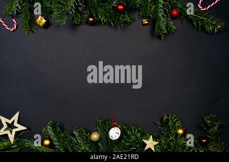 Christmas ornaments (Christmas baubles, stars and little presents) on black background framed by fir twigs Stock Photo