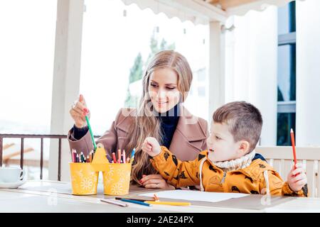 mother and son in the restaurant painted pencils before eating Stock Photo