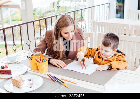 mother and son in the restaurant painted pencils before eating Stock Photo