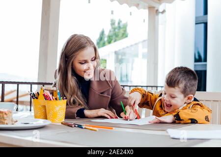 mother and son in the restaurant painted pencils before eating Stock Photo