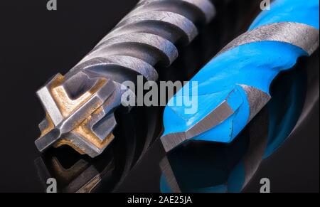 Drill bits cutting tips detail. Artistic still life with reflection on black background. Two spiral fluted tools. Masonry, concrete or stone drilling. Stock Photo