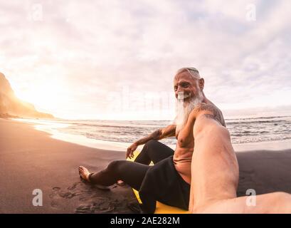Senior man taking selfie in surfing day - Mature hipster male having fun doing surf at sunset time