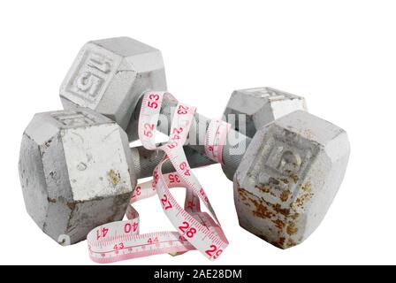 Pair of vintage free hand weights that are 15 fifteen pounds each on an isolated white background. A tape measure is wrapped them. Stock Photo