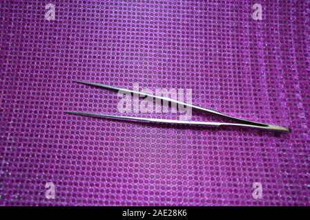 Steel pincer for working on a pink reflective background. Stock Photo