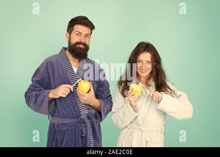 Keep teeth healthy. Healthy habits. Brush teeth every morning. Oral hygiene. Couple bathrobes hold toothbrushes and apples. Personal hygiene. Couple in love cleaning teeth. Freshness and cleanliness. Stock Photo