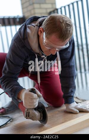 repair and decoration. a man cuts ceramic tiles with a grinder Stock Photo