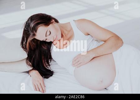 a pregnant woman is lying in bed waiting for the birth of a child Stock Photo