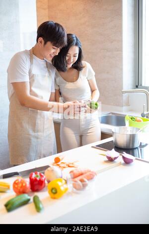 Happy young couple using smartphone in kitchen Stock Photo