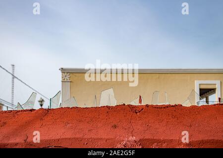 glass shards embedded ion top of red wall to stop intruders Stock Photo