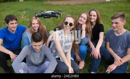 Cheerful friends are watching the flight of the drone. Stock Photo