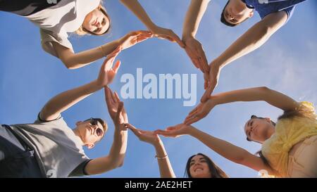 A group of friends makes a circle from the palms of their hands. Stock Photo