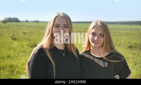 Portrait of two twin sisters in the field on a warm summer day Stock Photo