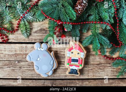 Homemade christmas gingerbreads painted as a mouse and Nutcracker on the wooden background with fir branches. Selective focus and place for text. Stock Photo