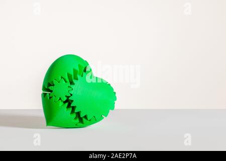 a green 3d printed heart on a white and grey background with a shadow behind Stock Photo