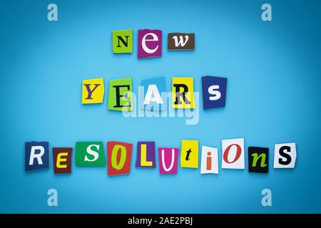 Text - New year's resolutions. Cut colorful letters on blue background. Writing on banner, card. Inscription, message on poster. Stock Photo