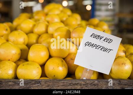 Pile of orange ruby grapefruit on the wooden table in the market. Fruit harvest. Local farm market. Healthy fruit. Vitamins. Stock Photo