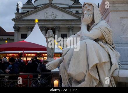 Berlin, Germany. 30th Nov, 2019. A figure of the Schiller monument by Reinhold Begas, holding her head in her hand, stands next to the Christmas market at Gendarmenmarkt. In the background you can see a part of the French Cathedral. Credit: Harald Tittel/dpa/Alamy Live News Stock Photo