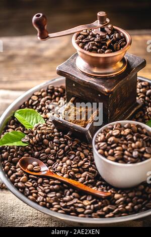 https://l450v.alamy.com/450v/2ae2xen/wooden-vintage-hand-coffee-grinder-and-cup-on-a-pile-of-brown-coffee-beans-grinding-fragrant-freshly-roasted-coffee-2ae2xen.jpg