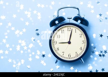 Alarm clock on a blue background with stars. The concept of preparing for sleep, an evening fairy tale, sweet dreams, etc. Stock Photo