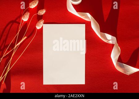 Empty paper card mock-up on the table with dry flowers and ribbon in natural sunlight Stock Photo