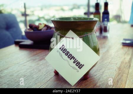 Reserved sign on restaurant table, outdoor summer terrace, toned image, soft grained effect Stock Photo