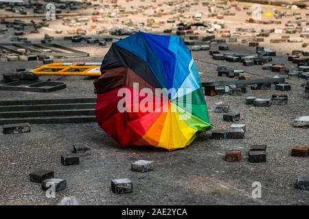 HongKong - November, 2019:  A broken rainbow colored umbrella on asphalt road between street barricades during 2019 Hongkong Protests, a.k.a. Umbrella Movement Stock Photo