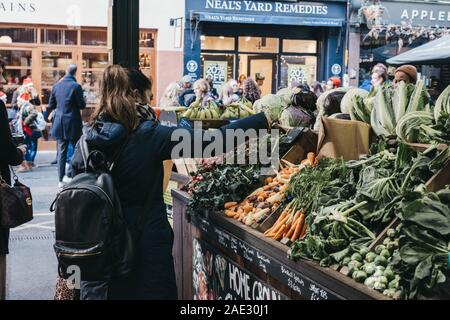 London, UK - November 29, 2019: Woman picking up fresh vegetables from Teds Veg stall in Borough Market, one of the largest and oldest food markets in Stock Photo