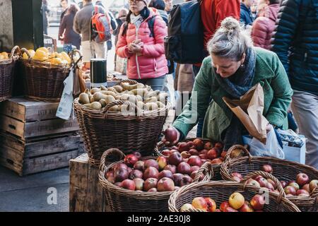 London, UK - November 29, 2019: Woman buying fresh apples from Teds Veg stall in Borough Market, one of the largest and oldest food markets in London. Stock Photo