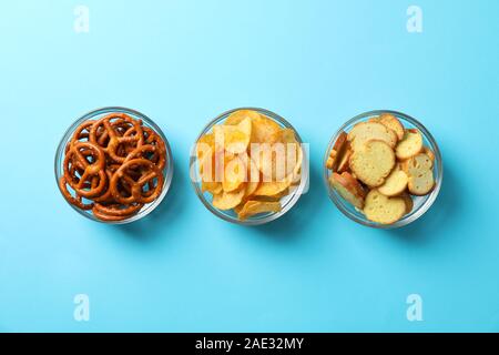 Crackers, chips. Beer snacks on blue background, space for text. Top view Stock Photo