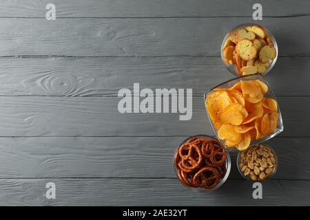 Beer snacks, potato chips, beer nuts on gray wooden background, space for text. Top view Stock Photo